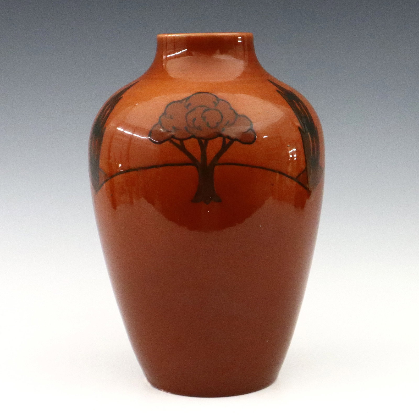 William Ault Art Pottery Vase: An early 20th century William Ault Pottery vase. Molded baluster form body with Art Deco tree design on a Brick Red ground. Impressed "Ault / England 5". Minor wear. 10 1/2" high. ESTIMATE $100-200