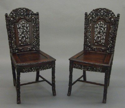 Pr of Chinese side chairs: A pair of 19th century Chinese Carved Hardwood side chairs. Shaped crests with elaborate carved Dragon design with foliage and pierced detail over pierced backs with songbirds in a garden, shaped pane