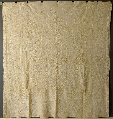 Trapunto bed covering: A 19th century American Trapunto bed covering. White with central flower basket with songbird corners framed with a "Vintage" border. Inscribed "Lydia A Parker, June 29th, 1853" below the central bask