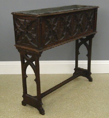Gothic Revival planter: A late 19th century Gothic Revival Period Oak planter. Molded top with open well and Tin liner, paneled sides with quatrefoil and foliate carved decoration on a stretched base with reticulated arched