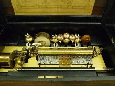 Swiss Music Box: A 19th Century Swiss Music Box. Burl Walnut music Box with string inlay and Ebony case that opens to reveal a pipe organ, a drum, a castanet, and Seven bells with Six birds. Interior also includes a r