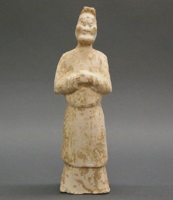 Chinese Tomb Figure: A Chinese Terracotta Tomb Figure. Stylized figure of a Man shown standing, with his hands clasped together at his chest. Remnants of paint are evident. Wear and minor losses. 10 1/2" high. ESTIMATE $1