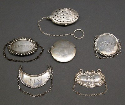 6 pc of Sterling: Six Pieces of American & English Sterling. Including One match safe by William Neale (1907), One clam shell form tea infuser, and Four liquor labels by both American and English silversmiths. Minor we