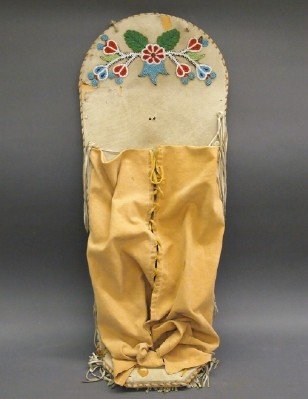 Nez Perce Cradleboard: A Nez Perce Beaded Hide Cradleboard. Hide wrapped board with canvas cover has floral beadwork decorating the top portion. No apparent markings. Losses to the hide, some discoloration, wear overall. 14