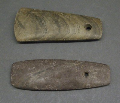 2 Drilled Adzes: Two Native American Adzes. Each stone is of rounded rectangular, and slightly tapered, form and contains a single hole. Minor nicks noted to the edges. 4" & 4 3/8" long. ESTIMATE $50-75