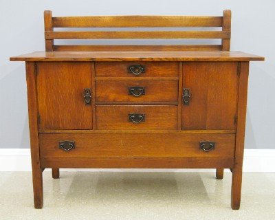 Gustav Stickley sideboard: An American Arts and Crafts Period Oak Sideboard, by Gustav Stickley, Model #814 1/2. Oak construction throughout with a short slatted backsplash over a plank top and three dovetailed central drawers 