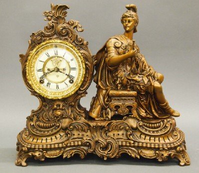 Ansonia "Knight" Clock: A Turn of the Century Ansonia "Knight" Figural Mantle Clock. Eight day time and strike movement with open escapement and enameled Porcelain dial. Patinated metal Ostentatious Rococo style case and bas