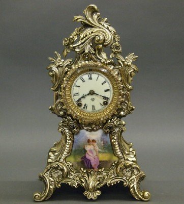 Ansonia "Amphion" Clock: A Turn of the Century Ansonia "Amphion" Mantle Clock. Eight day time and strike spring driven movement with enameled Porcelain dial. Ostentatious Gilt metal case with paste Brilliants about the dial a
