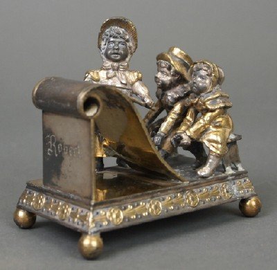 Simpson, Hall, Miller & Co. Napkin Ring: A 19th Century Simpson, Hall, Miller & Co. Silver Plate Figural Kate Greenaway Napkin Ring. Finely crafted napkin ring is adorned with three Figures of School children having a lesson, decorated with 