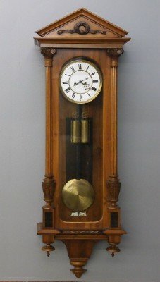 Vienna Regulator wall clock: A 19th Century Vienna Regulator Wall Clock. Walnut case with carved pediment, and applied fluted columns and carved capitals. Weight driven 8-day time and strike movement with two part porcelain dial