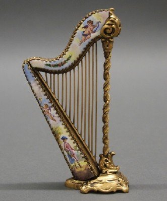 Austrian Miniature Harp: A Turn of the Century Austrian Miniature Harp. Consisting of ormolu and enamel with Cherub, swag, and Courting motifs. Unmarked. Minor wear. 5" high. ESTIMATE $300-500