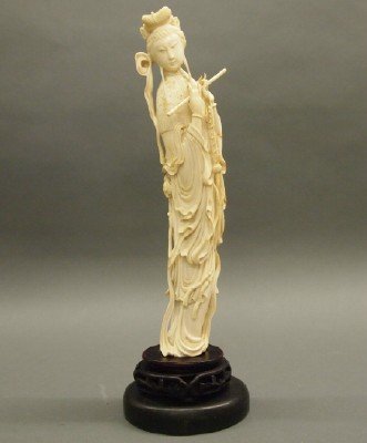 Chinese Ivory Figure of a Woman: A Late 19th Century Chinese Carved Ivory Figure of a Woman. Shown in long, flowing robes and playing a flute; mounted on a conforming wood base. Appears to be unmarked, but was not removed from base.