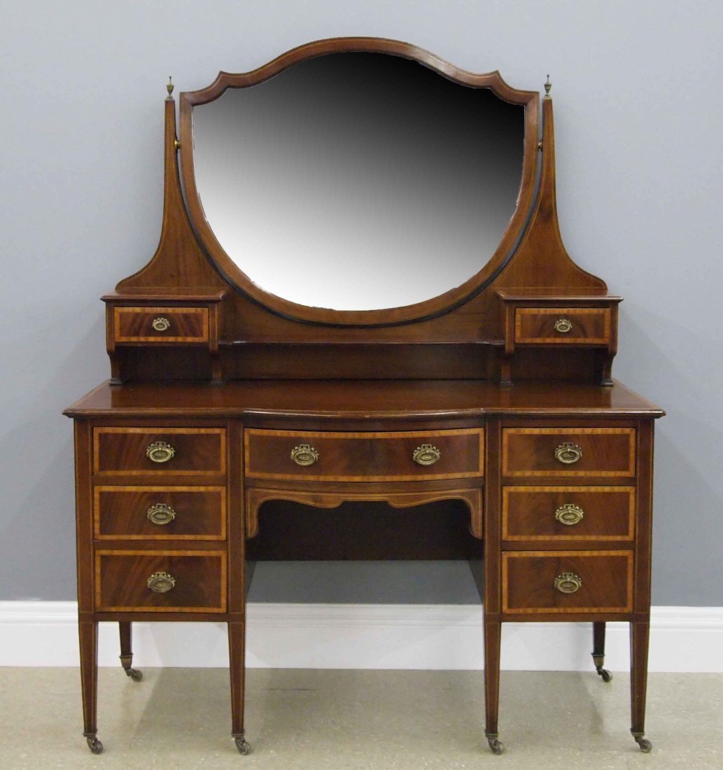 Mahogany Dressing Table: An Early 20th Century Dressing Table. Banded mahogany with string inlay boasts an upper portion consisting of a Shield form mirror with Two handkerchief boxes at either side, above a lower section com