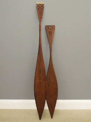 2 Maori Paddles: Two Carved Wood Maori Canoe (Waka) Paddles. Similarly designed, each with carved and pierced designs at the handle and carved motifs at the blades; one with metal at the tip of the handle. Wear and so