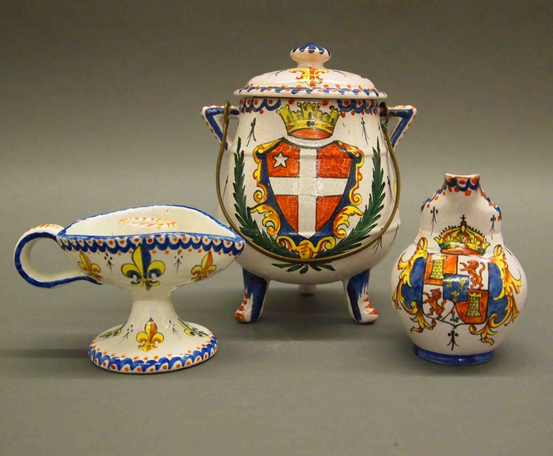 3 pcs CA French Faience: A Group of Three Pieces of Late 19th/Early 20th Century CA French Faience. Including a chamberstick, a creamer, and a covered pot on a tripod base with metal handle; each is decorated with an Armorial