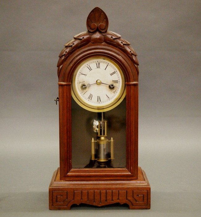 Kroeber "Snow Drop" shelf clock: A late 19th century Kroeber "Snow Drop" model shelf clock. 30 hr time only movement. Walnut case with carved detail. Old finish with minor wear, discoloration on dial. 15" high. ESTIMATE $200-300