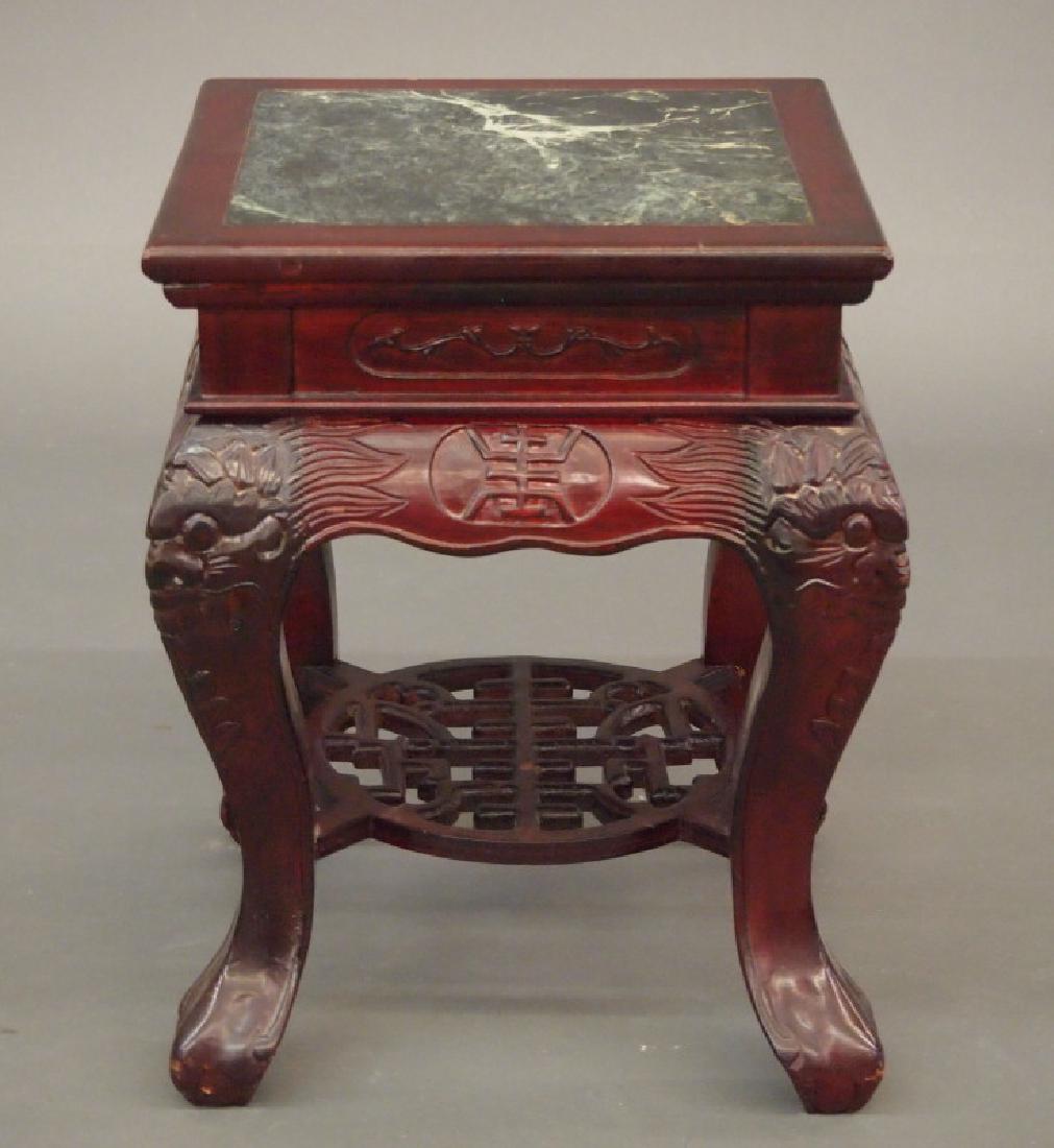 Chinese stand: A 20th century Chinese carved hardwood stand. Square top inset Verde marble, raised on four modified cabriole legs with carved mask knees, joined by a pierced shelf stretcher. Some minor wear. 12 x 12