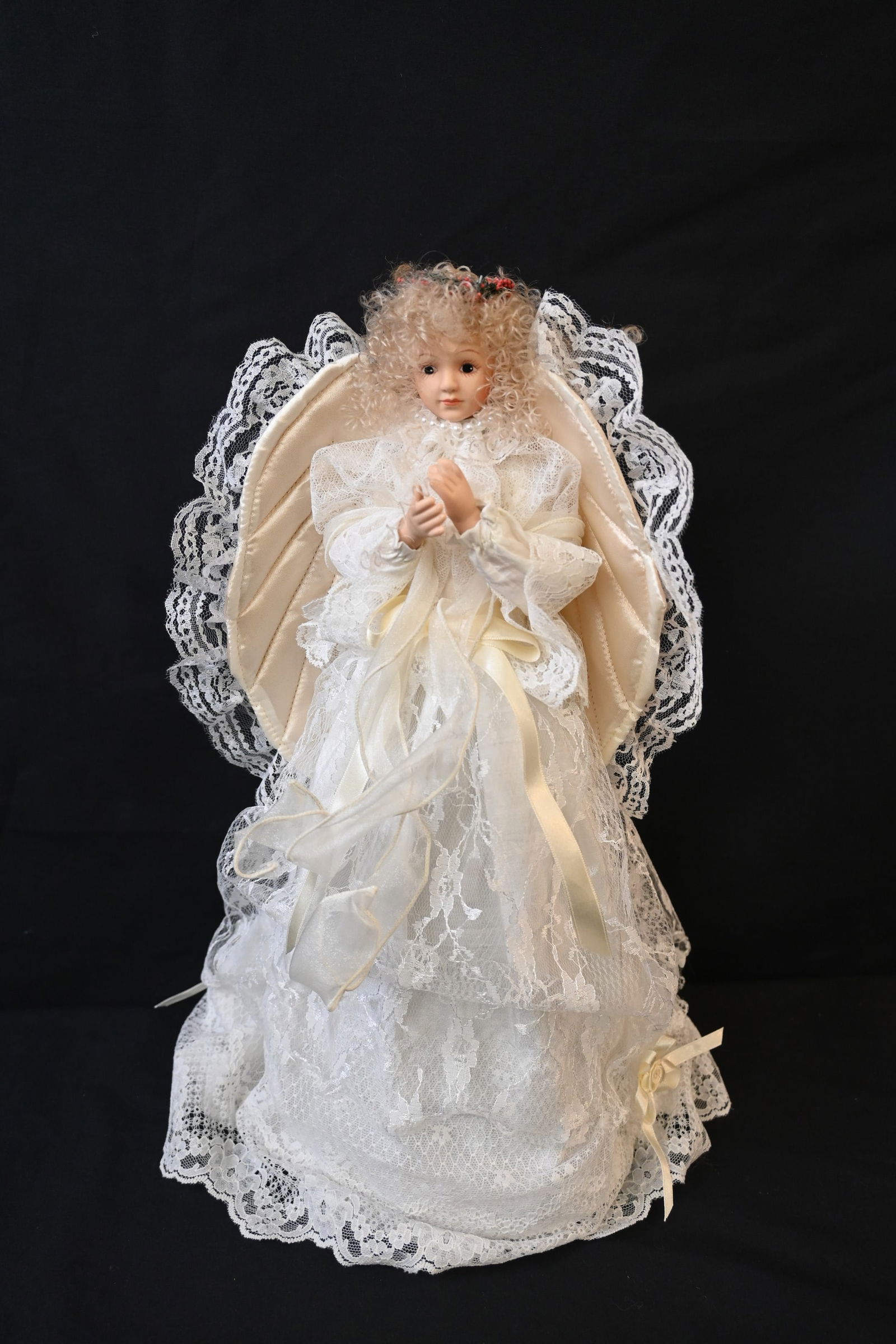 vintage or collectible porcelain angel doll or tree topper: This delicately crafted collectible doll features a porcelain or bisque head and hands with a soft fabric body. She is dressed in light-colored lace and satin, adorned with ribbons and likely beads, a