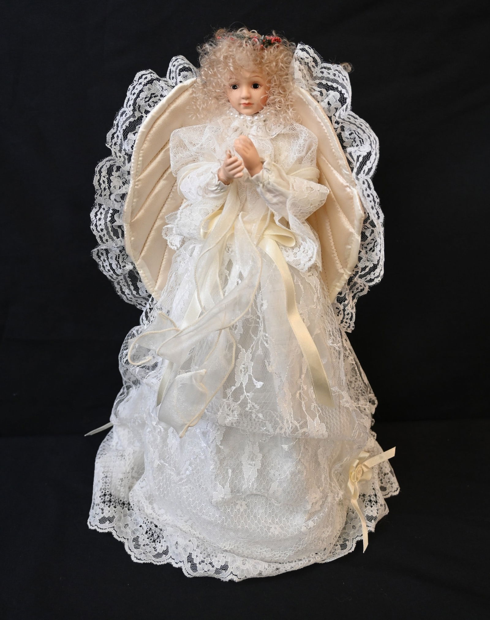 vintage or collectible porcelain angel doll or tree topper: This delicately crafted collectible doll features a porcelain or bisque head and hands with a soft fabric body. She is dressed in light-colored lace and satin, adorned with ribbons and likely beads, a